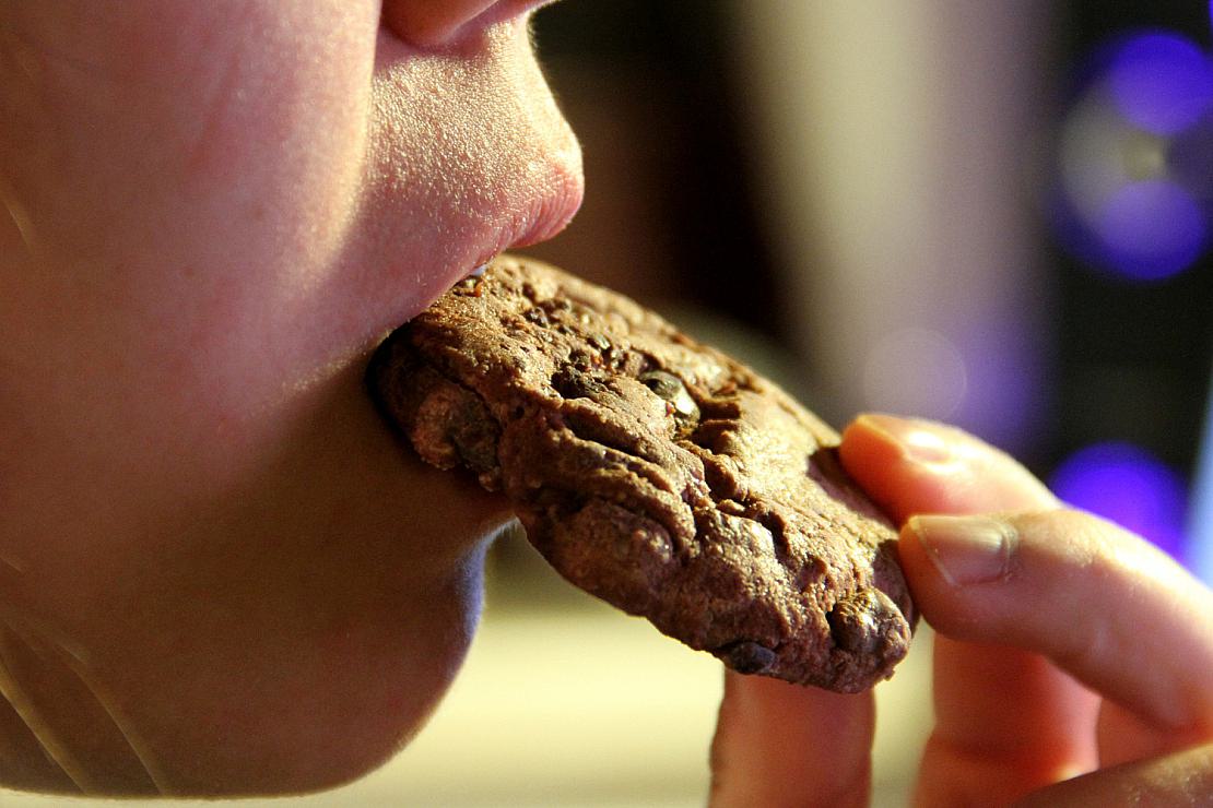 Junges Mädchen isst einen Schokoladenkeks (Archiv), via
