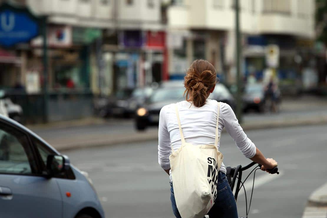 Junge Frau auf Fahrrad im Straßenverkehr (Archiv), via