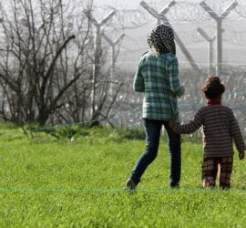 Flüchtlinge vor einem Grenzzaun (Archiv)