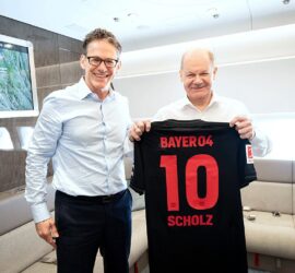 Bayer-Chef überreicht Scholz Leverkussen-Trikot am 15.04.2024, Kugler/Bundesregierung via